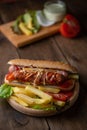 Vertical shot of a homemade hotdog sandwich with french fries on a wooden plate on the table