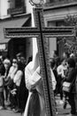 Vertical shot of a hooded penitent holding a cross during the Holy Week in Madrid