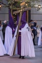 Vertical shot of a hooded penitent holding a cross during the Holy Week in Madrid