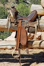 Vertical shot of a horse saddle on a wooden fence
