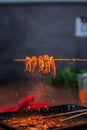 Vertical shot of hot spicy octopus legs on wooden sticks frying on a grill stove