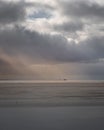 Vertical shot of a huge clouds with sunrays on the beach at sunset Royalty Free Stock Photo