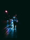 Vertical shot of a human silhouette walking along an urban sidewalk