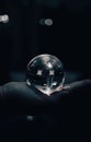 Vertical shot of a human's palm holding a shining glass ball on an isolated background