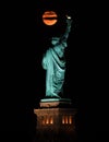 Vertical shot of the iconic Statue of Liberty and a full moon at night