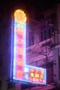 Vertical shot of an illuminated colorful neon sign hanging on a building in Kowloon City at night