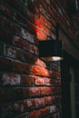 Vertical shot of an illuminated lightbulb on a brown brick wall