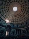 Vertical shot inside Pantheon with a crowd and sunlight