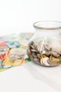 Vertical shot of a jar with coins and Australian dollar banknotes on the white background Royalty Free Stock Photo