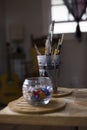 Vertical shot of a jar of marbles and cup of paint brushes indoors Royalty Free Stock Photo