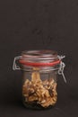 Vertical shot of a jar of walnuts under the lights on a brown surface