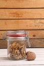 Vertical shot of a jar of walnuts under the lights on a wooden table