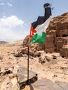 Vertical shot of the Jordanian flag flapping in the wind set atop a rock wall