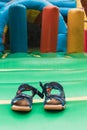 Vertical shot of kids sandals left in front of the inflatable trampoline Royalty Free Stock Photo