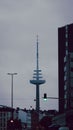 Vertical shot of the Kiel television tower on bustling street corner on a clouded day