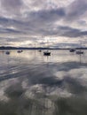 Vertical shot of a lake with silhouettes of boats under a cloudy sky