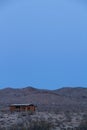 Vertical shot of a landscape with an old wooden barn on it and a mountain range in the background Royalty Free Stock Photo