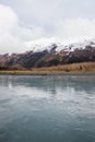 Vertical shot of a large river with a meadow and high snowy mountains in Alaska Royalty Free Stock Photo