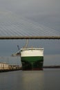 Vertical shot of a large ship under a bridge by the water in Savannah, Georgia, USA