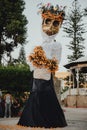 A vertical shot of a large wooden skeleton sculpture with flowers for the La Catrina holiday