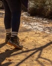 Vertical shot of the legs of a hiker wearing dirty shoes walking on a dirt trail