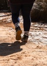 Vertical shot of the legs of a hiker wearing dirty shoes walking on a dirt trail