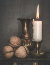 Vertical shot of lighting candle, bronze vase, and walnuts in a table