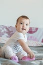 Vertical shot. Little baby smiling sits on bed at home