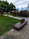 Vertical shot of a llamas park in Santander, Spain with an empty wooden bench and curvy walkway