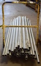 Vertical shot of long silver pipes on a yellow rolling cart in a department store