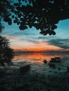 Vertical shot of a majestic sunset view over a reflective calm seascape with silhouettes of boats