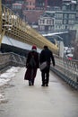 Vertical shot of a male and a female walking through the bridge on a cold winter day