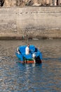 Vertical shot of a male fishing in a blue boat near the coastline in Madeira Portugal
