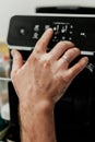 Vertical shot of a male hand with a ring on pressing buttons on a black machine. Royalty Free Stock Photo