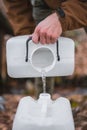 Vertical shot of a male's hands pouring water from one plastic canister to another