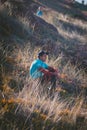 Vertical shot of a male surfer relaxing at the grassy shore of the ocean