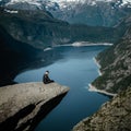 Vertical shot of a male at Troll's Tongue overlooking Lake Rasengan on Mount Skjeggedal in Norway Royalty Free Stock Photo