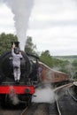 Vertical shot of a  man attaching a lamp to the front of a steam train at Grosmont station, the UK Royalty Free Stock Photo