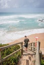 Vertical shot of a man going down the wooden stairs at the Praia de Nossa Senhora da Rocha, Portugal