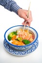 Vertical shot of a man holding chopsticks in a Thai Tofu Veggie dish in a traditional Thai bowl Royalty Free Stock Photo