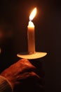 Vertical shot of a man holding a lit candle on the dark background Royalty Free Stock Photo