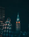 Vertical shot of a male looks at a tower with red lights of Philadelphia City Hall at night Royalty Free Stock Photo