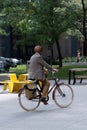 Vertical shot of a man riding an old-fashioned bike through TD Tower Plaza in Downtown Toronto