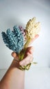 Vertical shot of man's hand holding a bouquet of artificial flowers Royalty Free Stock Photo