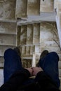 Vertical shot of a man sitting in the ruined staircase of an abandoned building Royalty Free Stock Photo