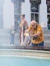 Vertical shot of a man taking a photo of a fountain with a smartphone in Lazarski square, Poznan