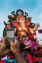 Vertical shot of a man taking a photo of Ganesha on the Ganpati Visarjan, Girgaon Chowpatty, India