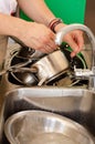 Vertical shot of a man washing pans in a scullery restaurant