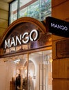 Vertical shot of the Mango clothing logo in front of their store at night