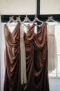 Vertical shot of matching bridesmaids dresses with named hangers hanging in a room